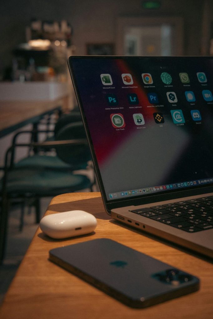 Laptop, smartphone, and earbuds on desk.