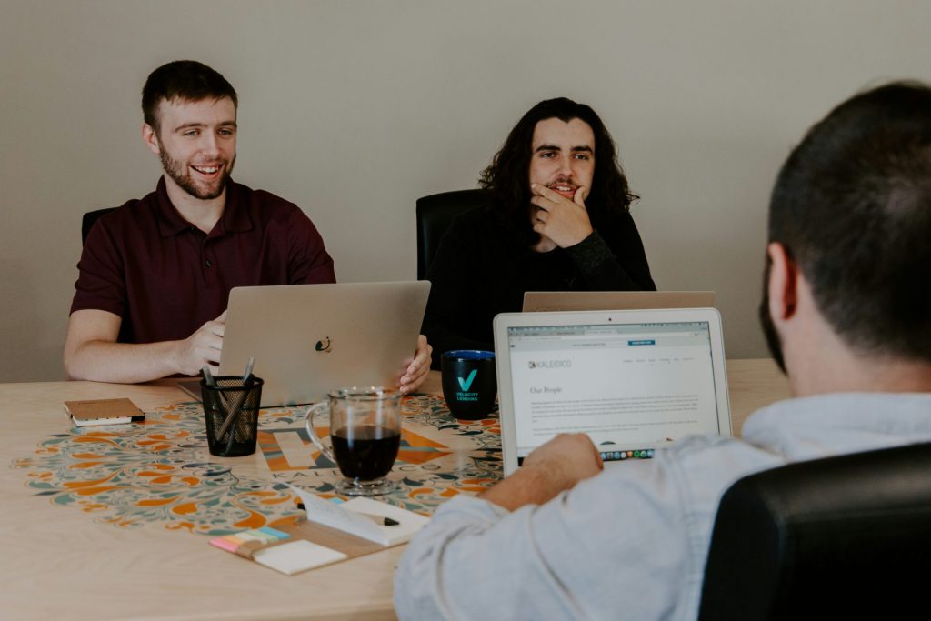 Two men discussing ideas while using laptops.