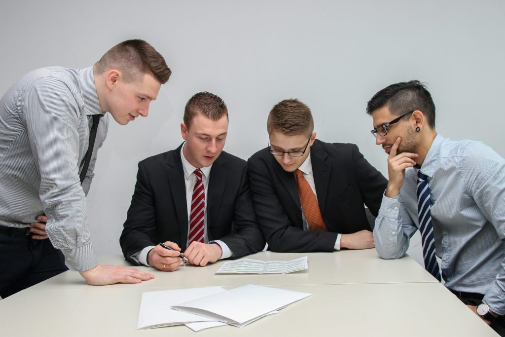 Four men in suits reviewing documents.